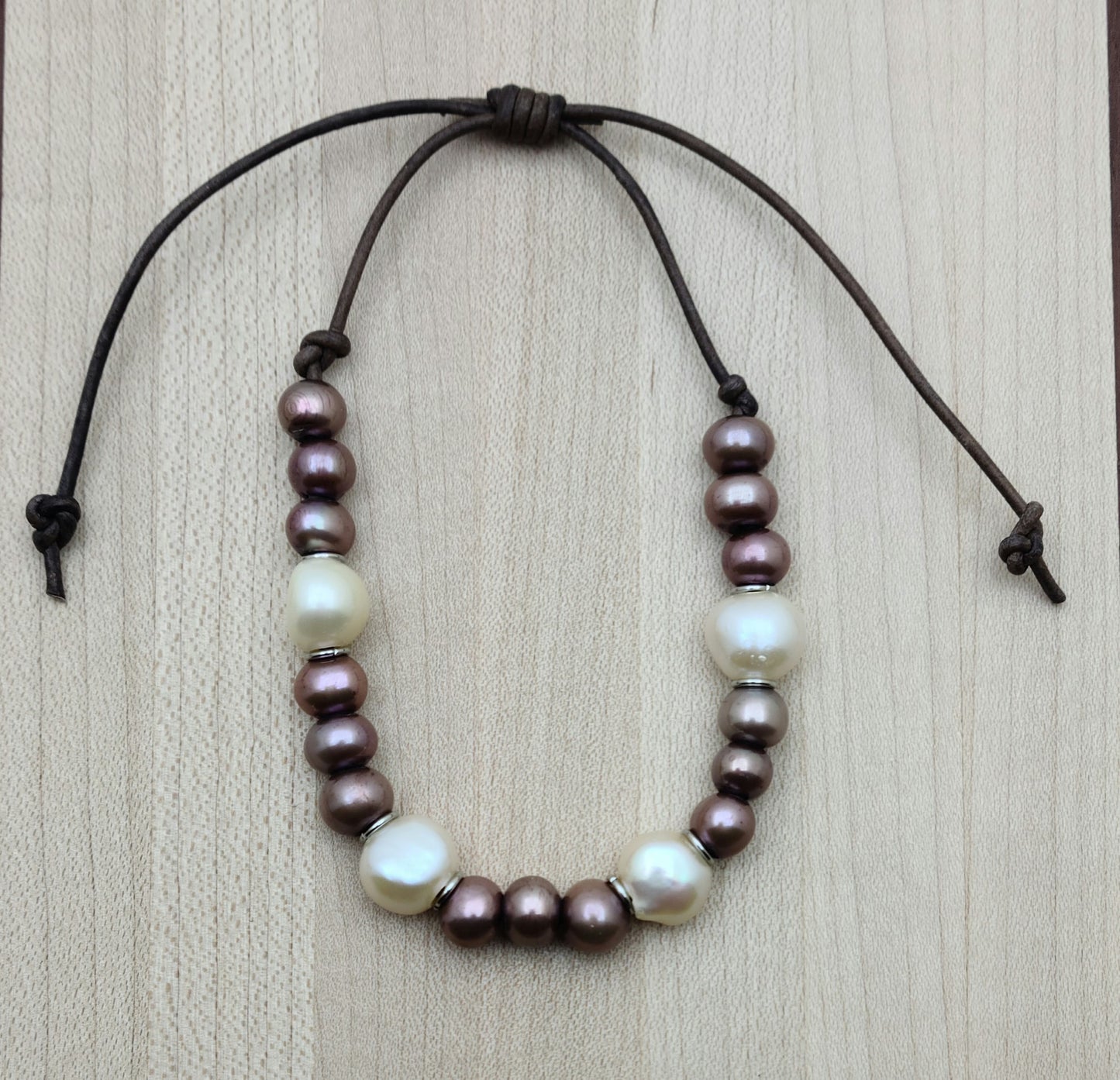 A casual leather slider bracelet of baroque freshwater in plum & cream with stainless steel rings for accent.