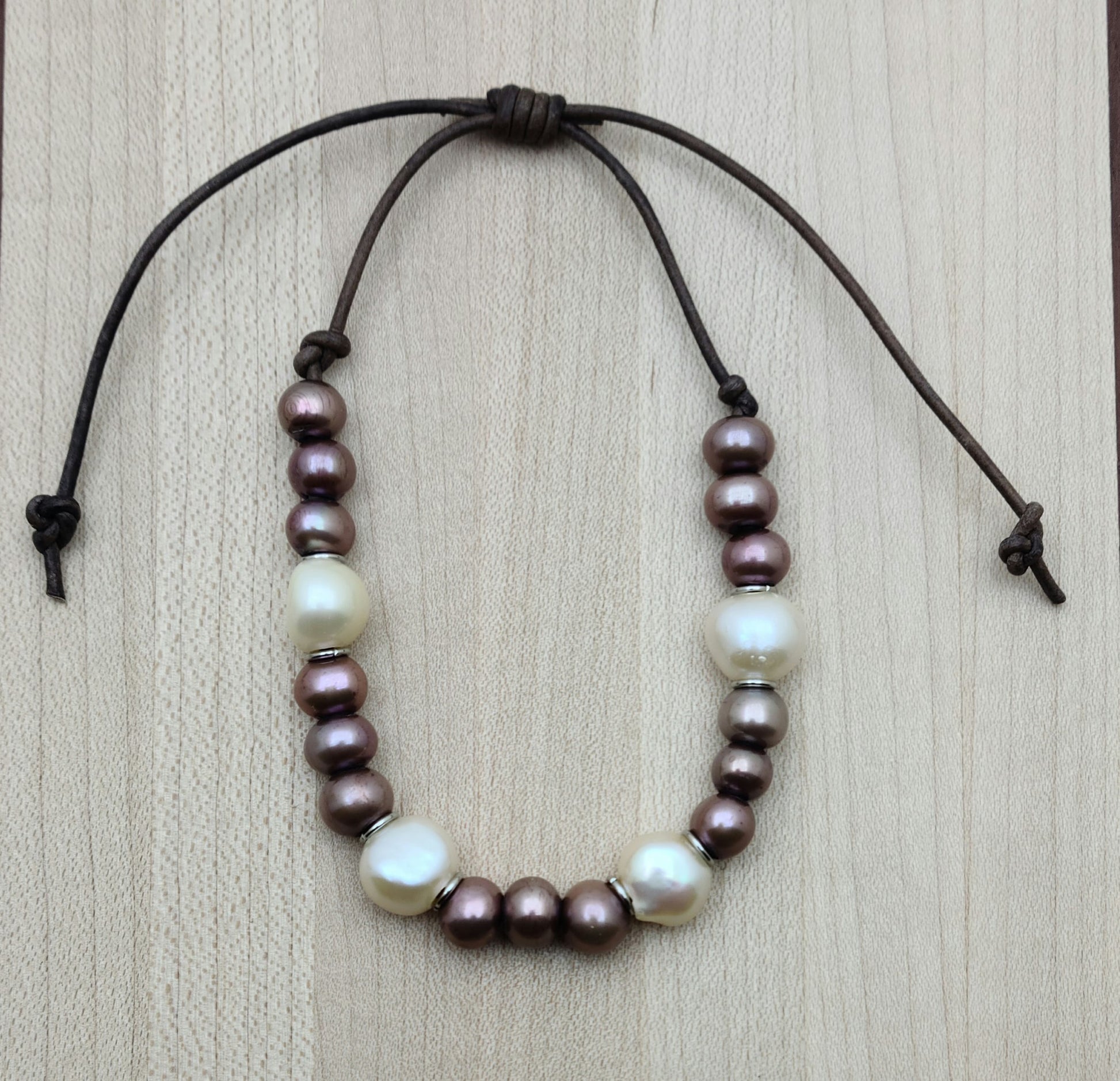 A casual leather slider bracelet of baroque freshwater in plum & cream with stainless steel rings for accent.
