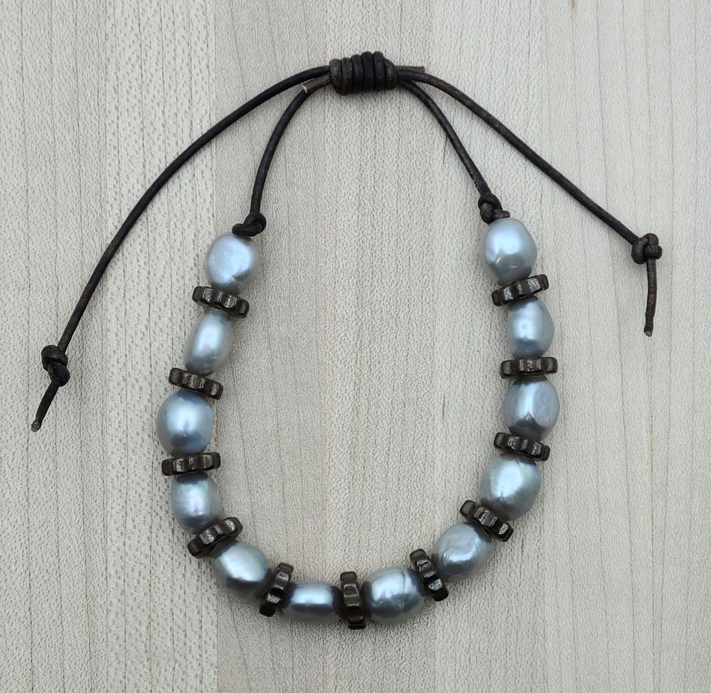 A casual leather slider bracelet of baroque freshwater in silver and antique copper plated ceramic steampunk styled beads.