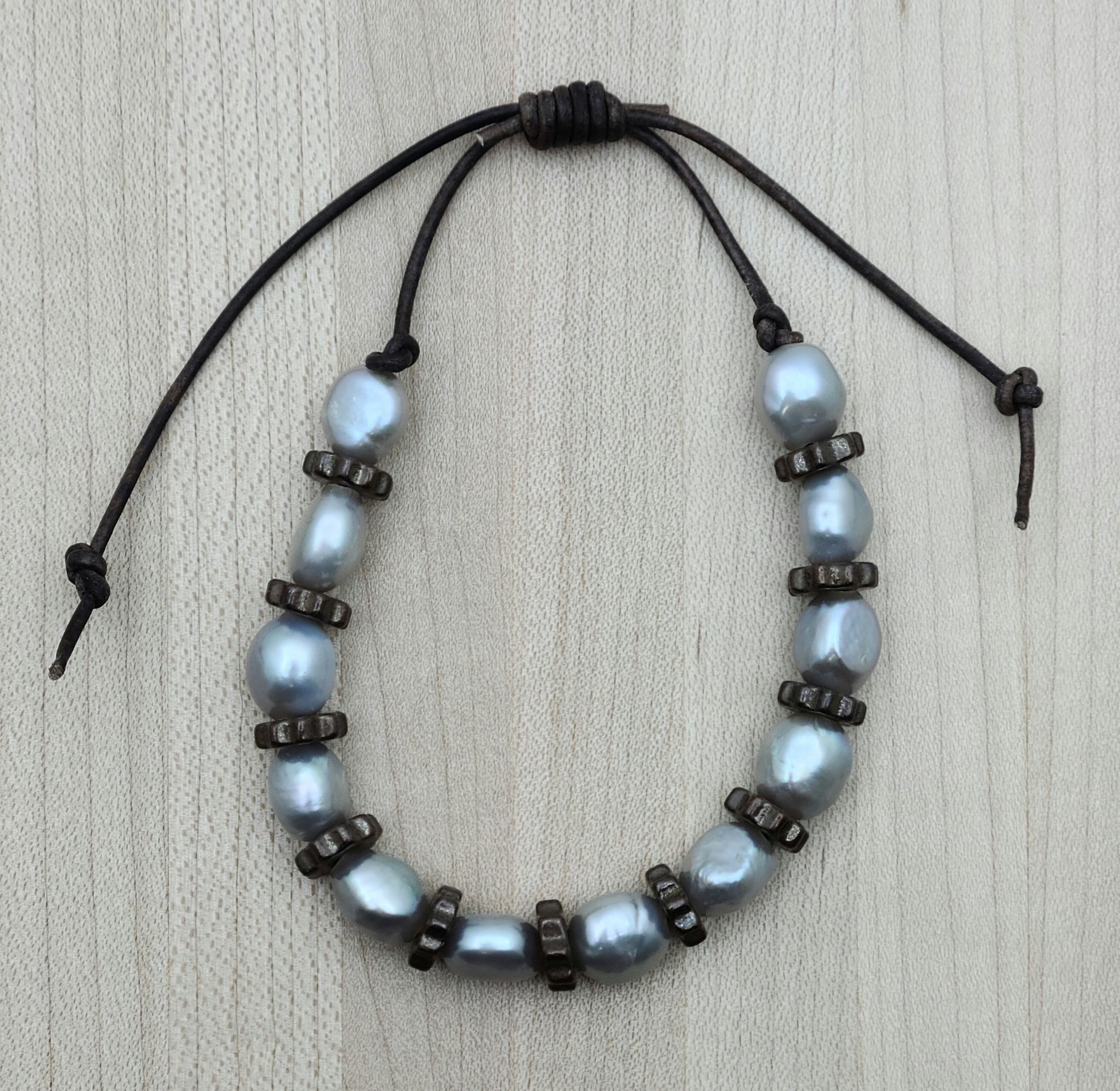 A casual leather slider bracelet of baroque freshwater in silver and antique copper plated ceramic steampunk styled beads.