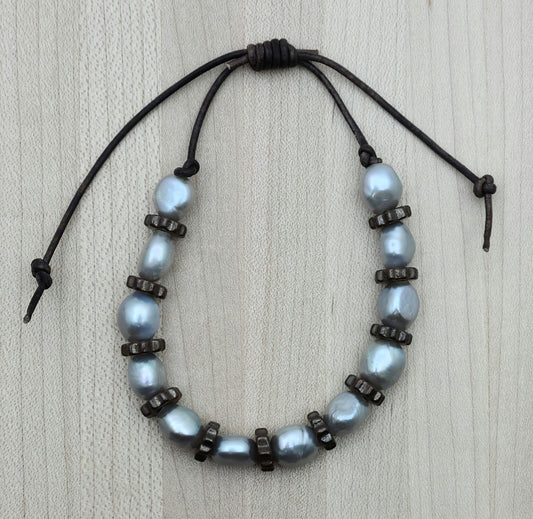 A casual leather slider bracelet of baroque freshwater in silver and antique copper plated ceramic steampunk styled beads.