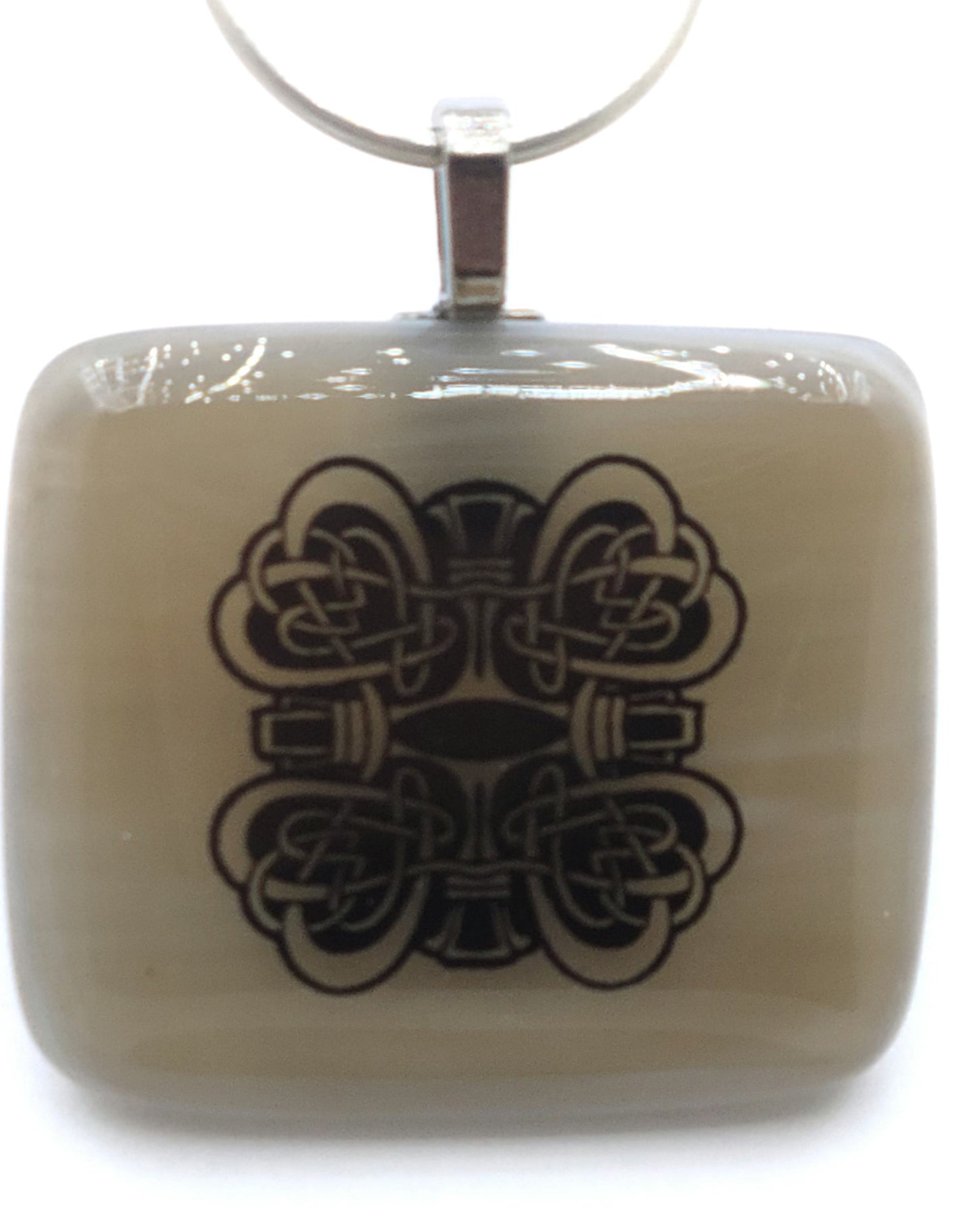 Celtic knotted hearts ornament this light tan fused glass pendant.