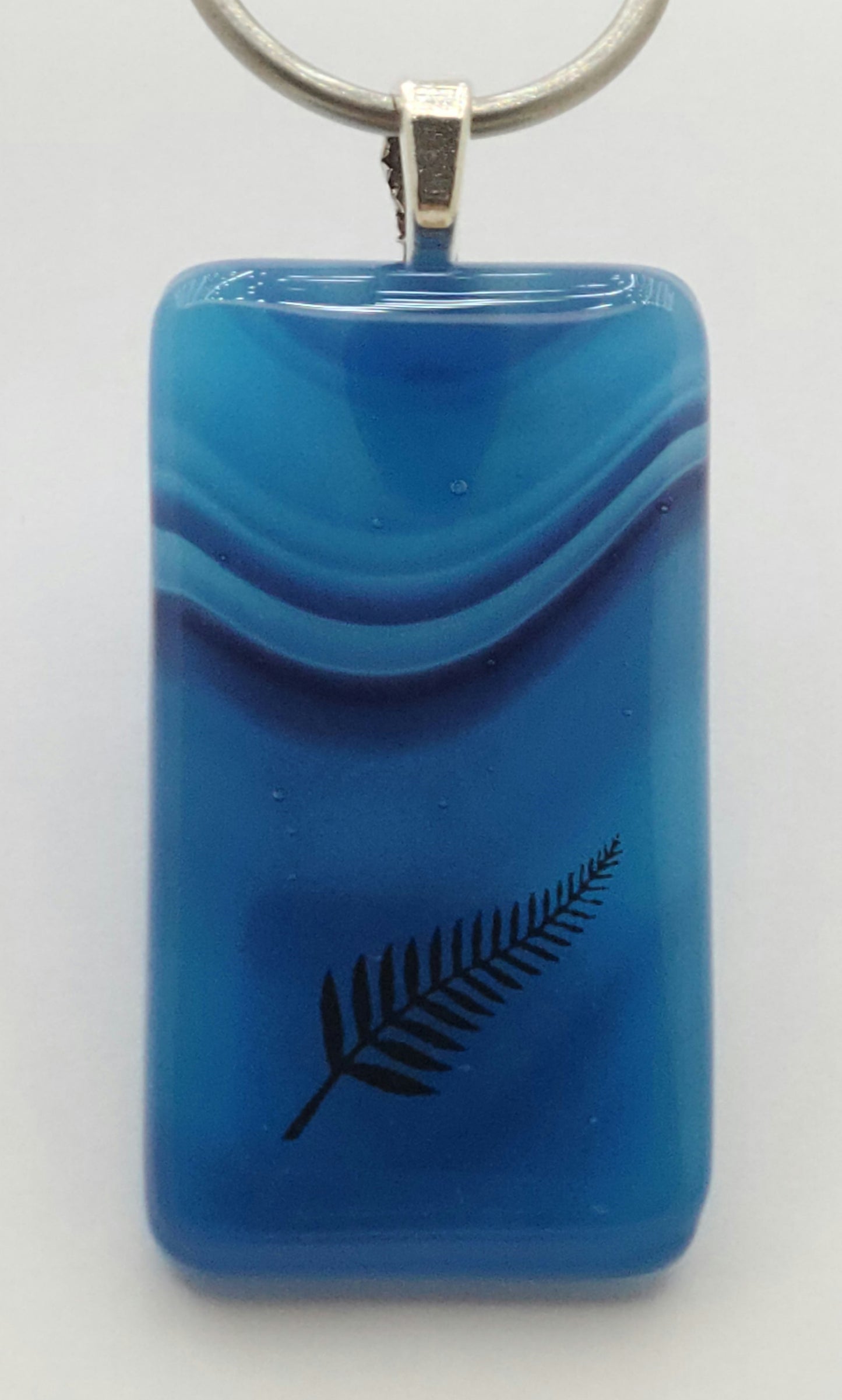 A single frond decorates this lovely blue shades fused glass pendant.