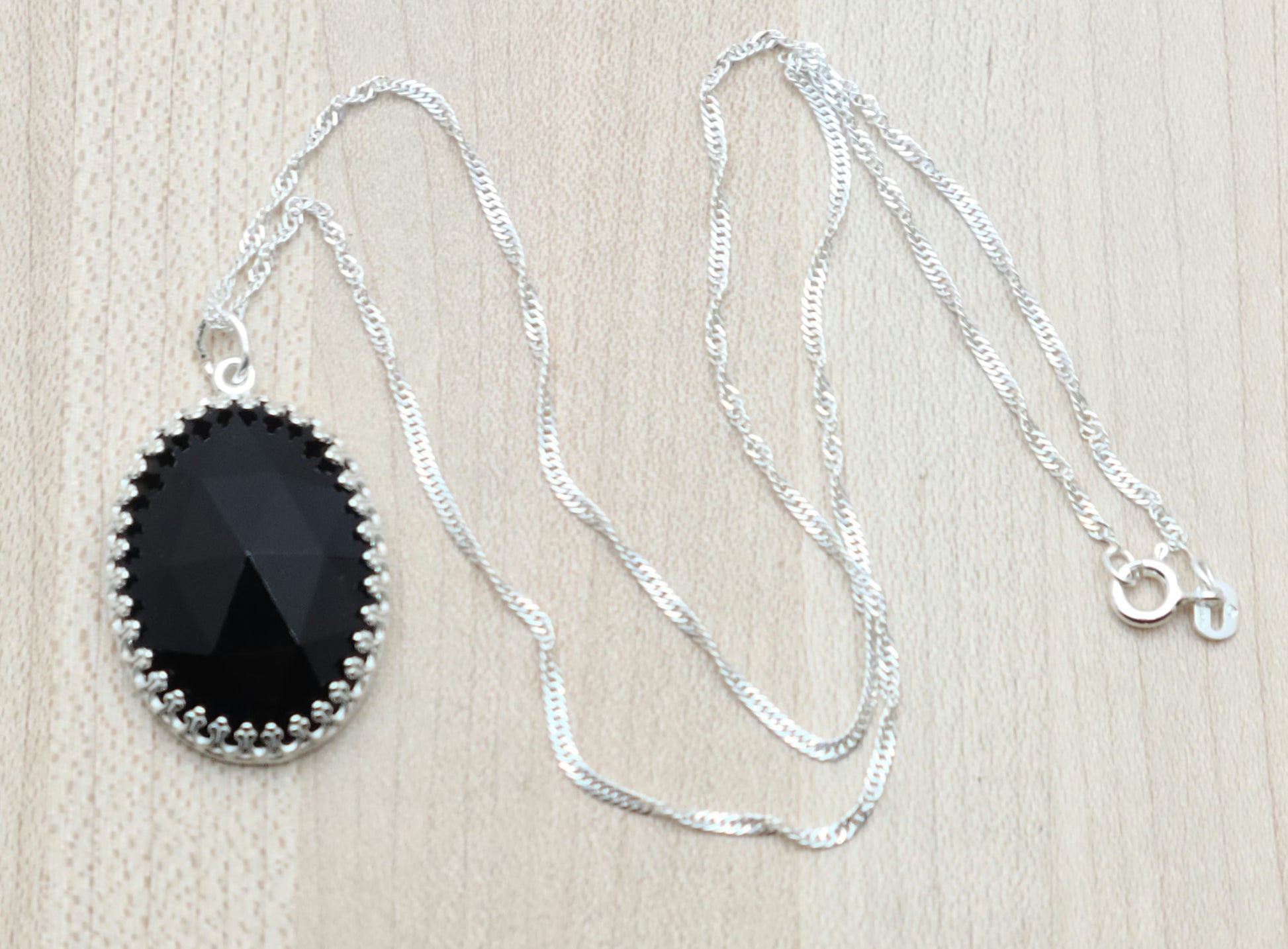 This Oval Faceted Onyx Drop, set in sterling silver, will add a touch of elegance to any outfit.