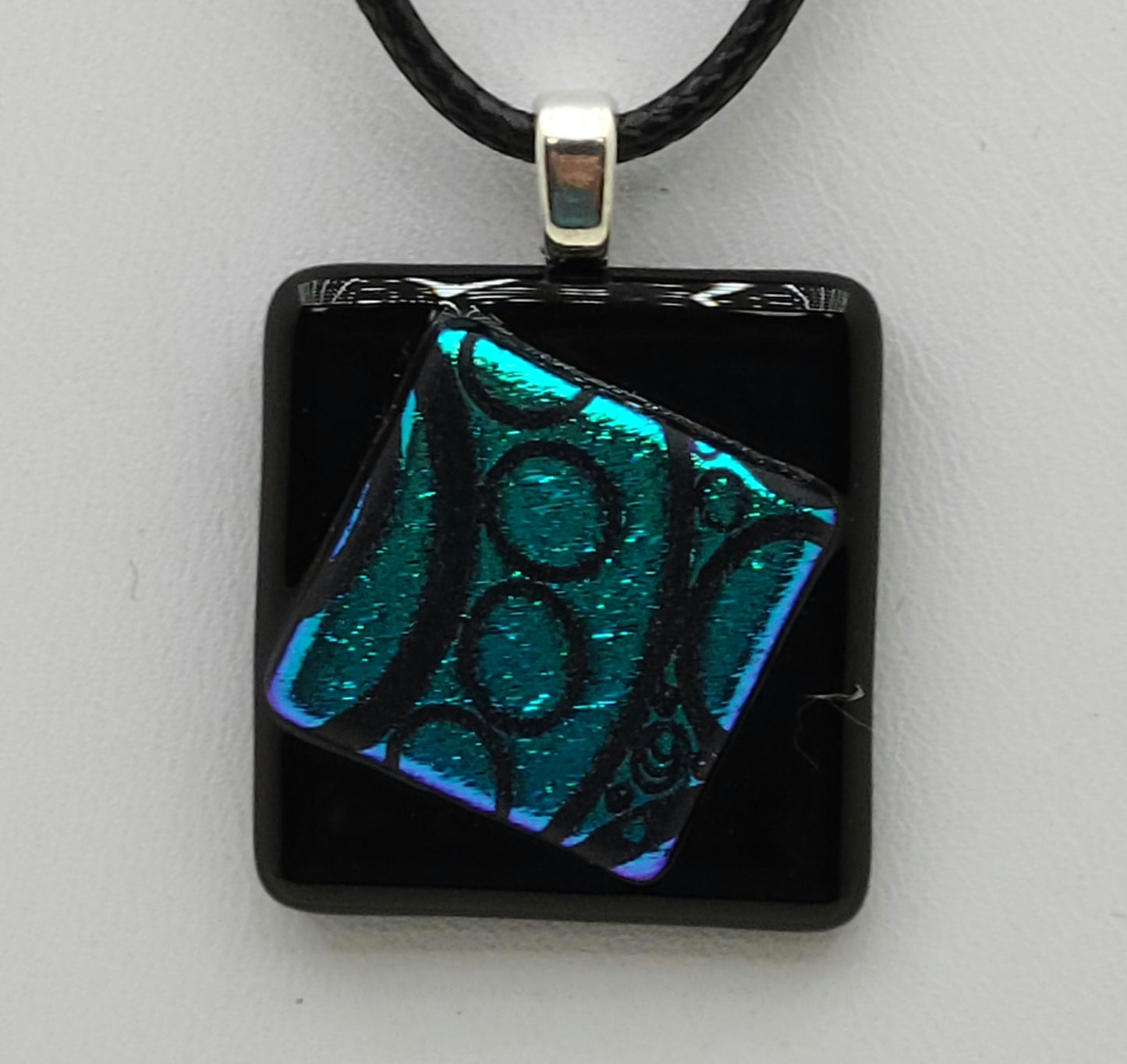 Tiny Cock-eyed teal dichroic square on black square Fused Glass Pendant