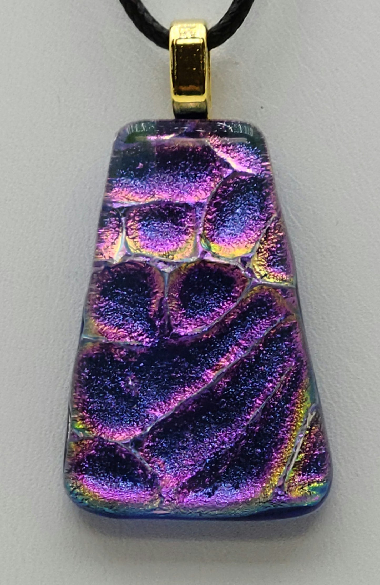 This lovely dichroic fused glass pendant is bluish purple with hints of gold & fuchsia.