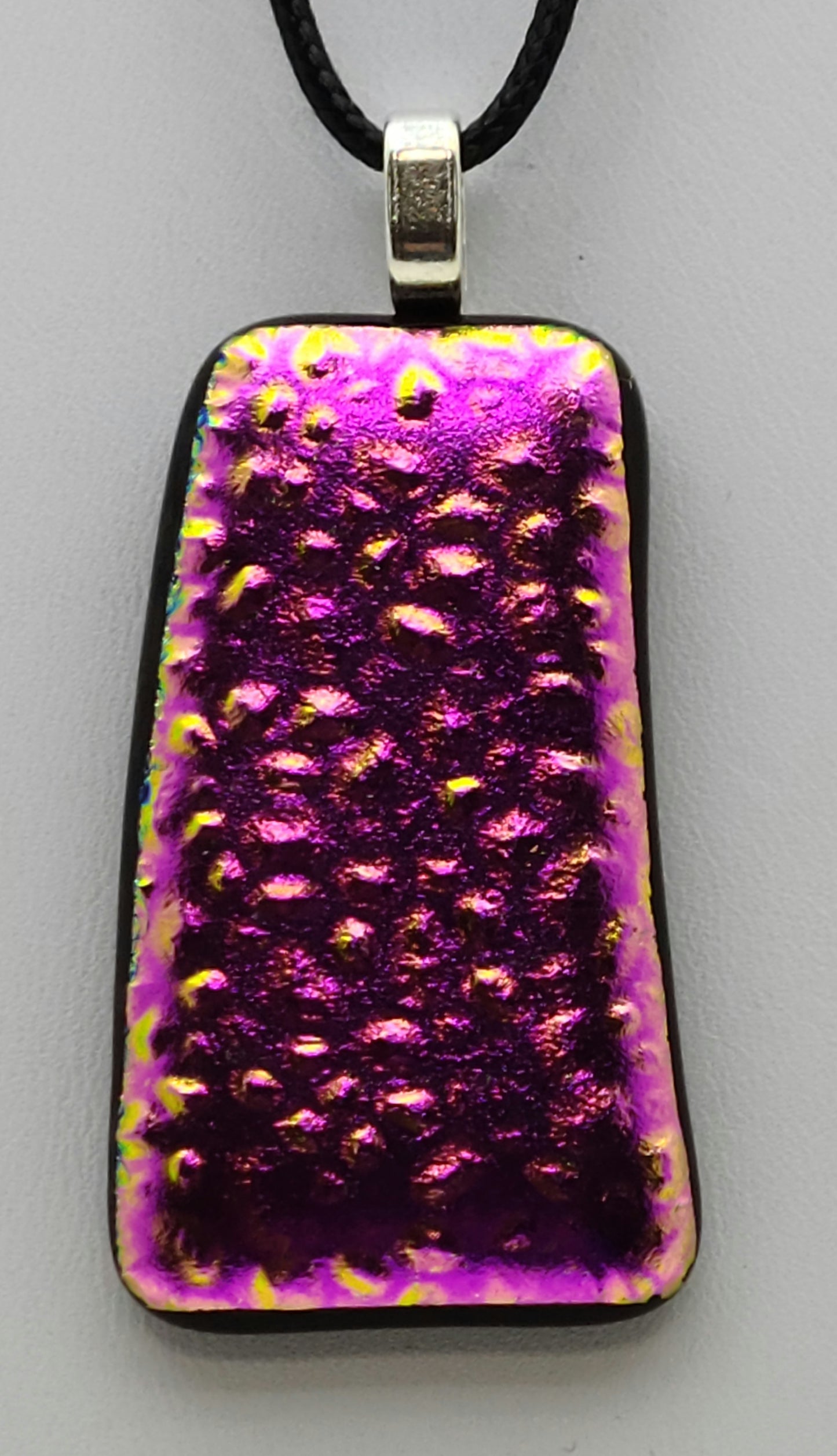 A bright pink, textured dichroic fused glass pendant.