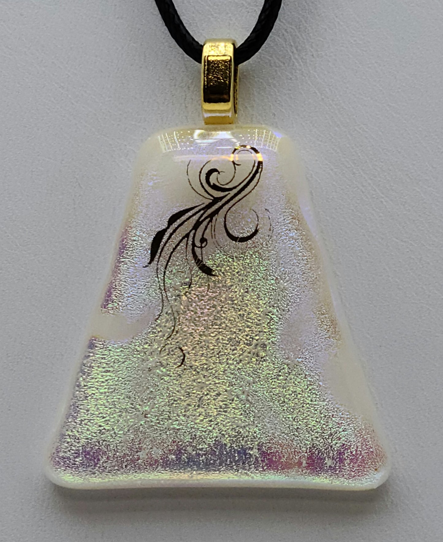 Light flitters on a rainbow with a gold flourish front & center in this dichroic fused glass pendant.