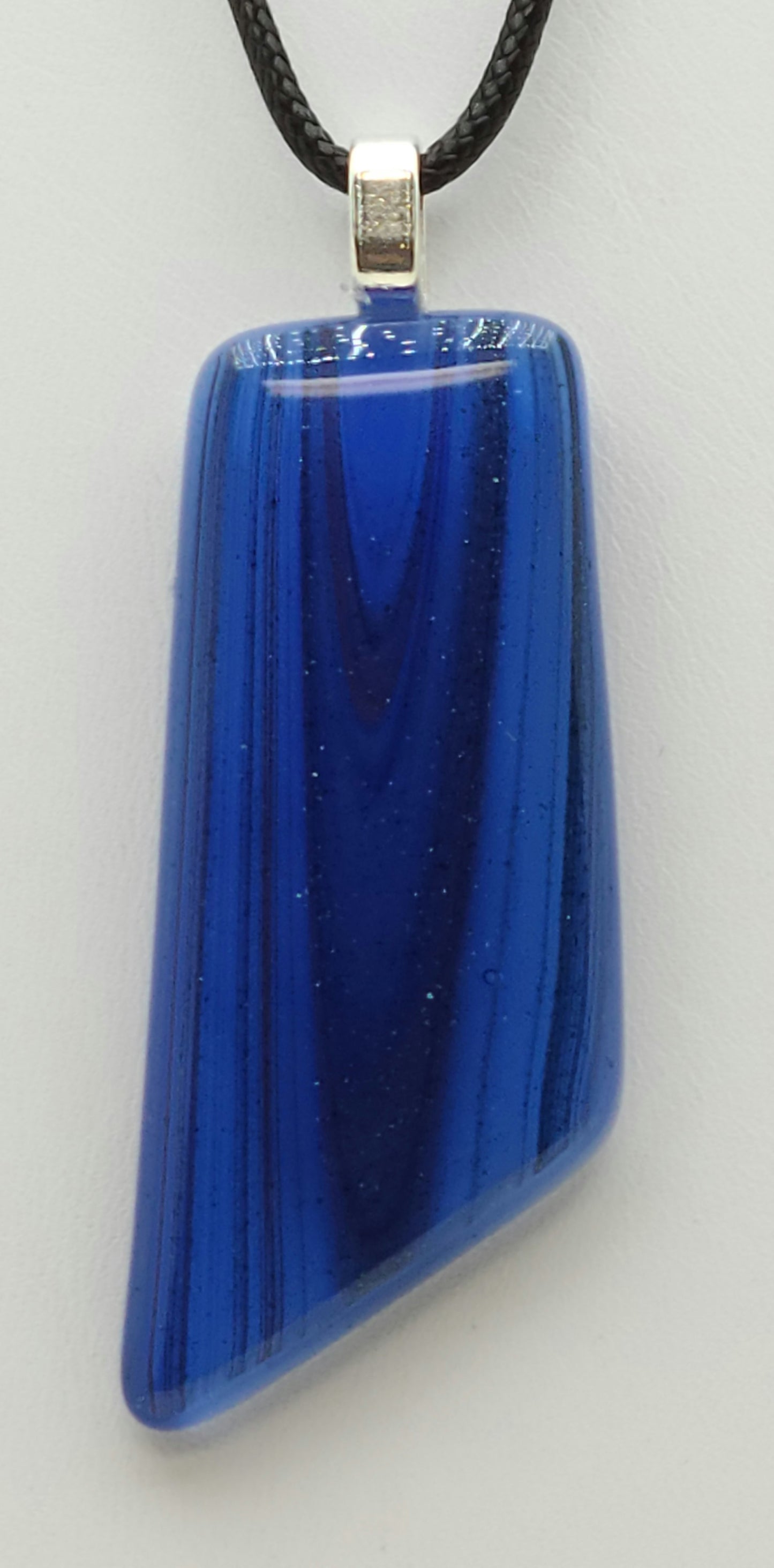 Glittery blue streaks run vertically on this velvety fused glass pendant.