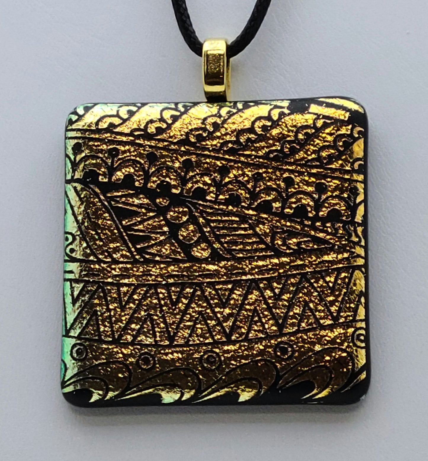 Etched tribal designs adorn gold crinkle dichroic glass in this pendant.