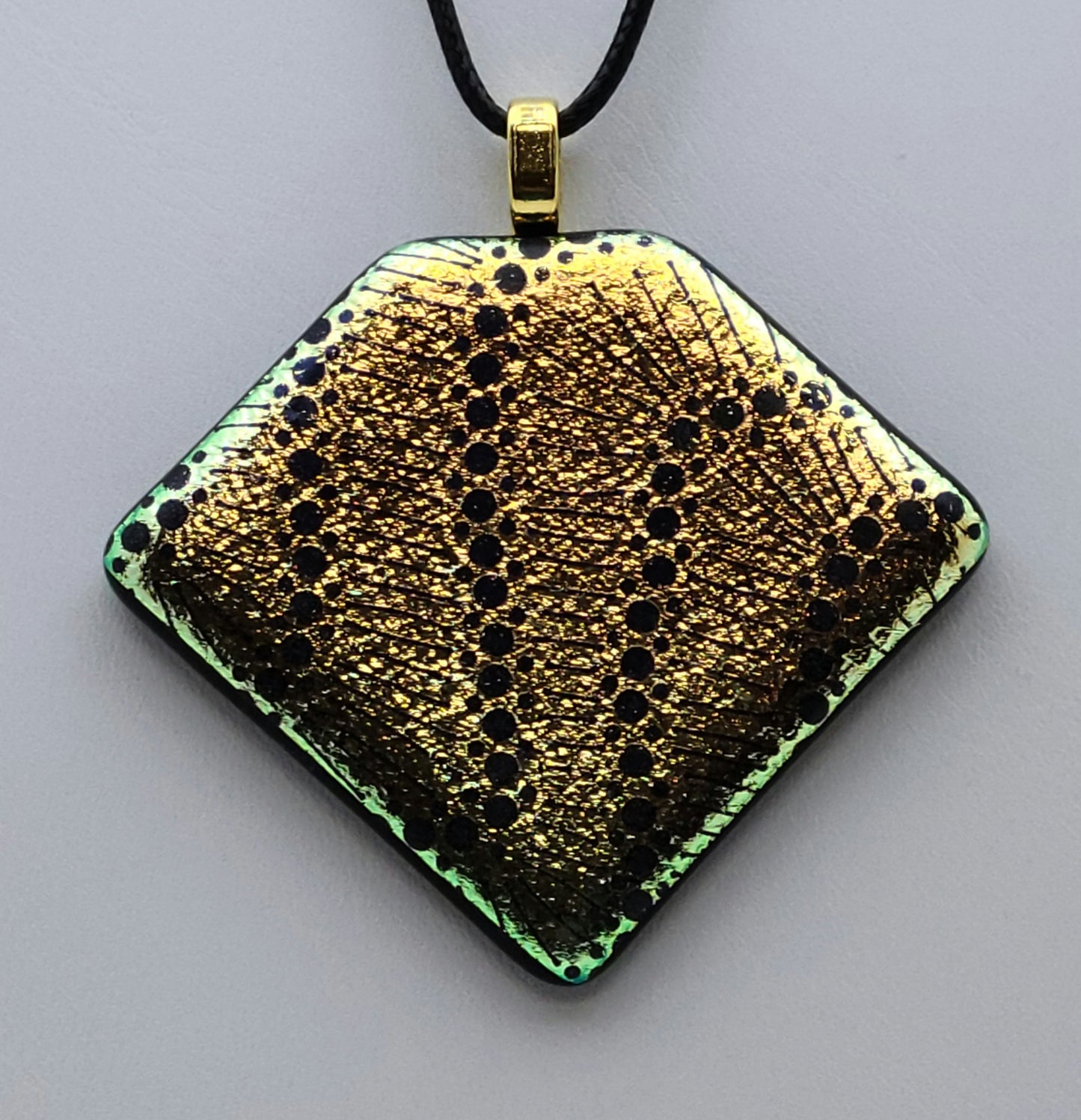 Black dots wander across gold crinkle dichroic glass in this pendant