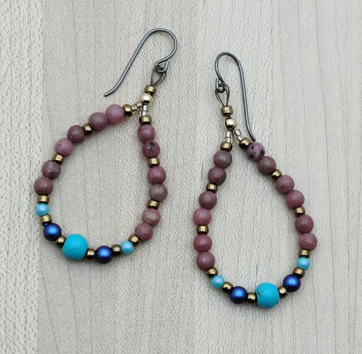 teardrop hoop earrings of dusty pink rhodonite, blue & turquoise crystal pearls, turquoise howlite, & bronze Miyuki seed beads. On niobium fish hooks