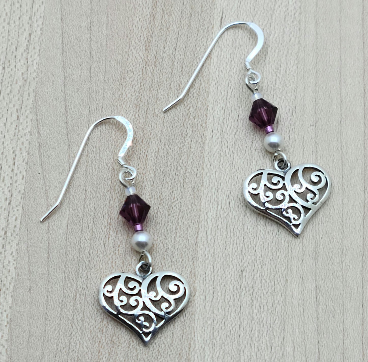 These sophisticated & sweet earrigs features luminous white freshwater pearls and vibrant amethyst crystals, accented by delicate filigree sterling silver hearts