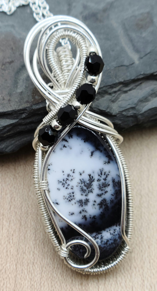 This fascinating dendrite stone has a scenic look to it. I framed it with woven silver filled wire and adorned it with tiny crystals