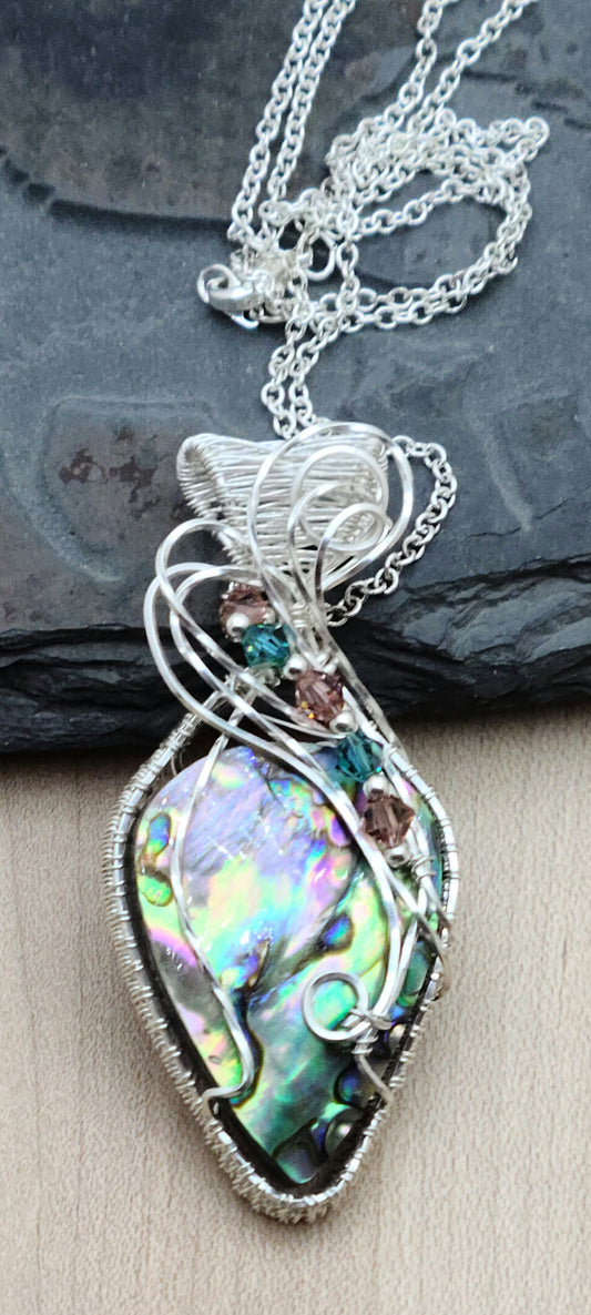 Prepare to be mesmerized by this radiant iridescent abalone shell pendant in a woven silver filled wire frame!