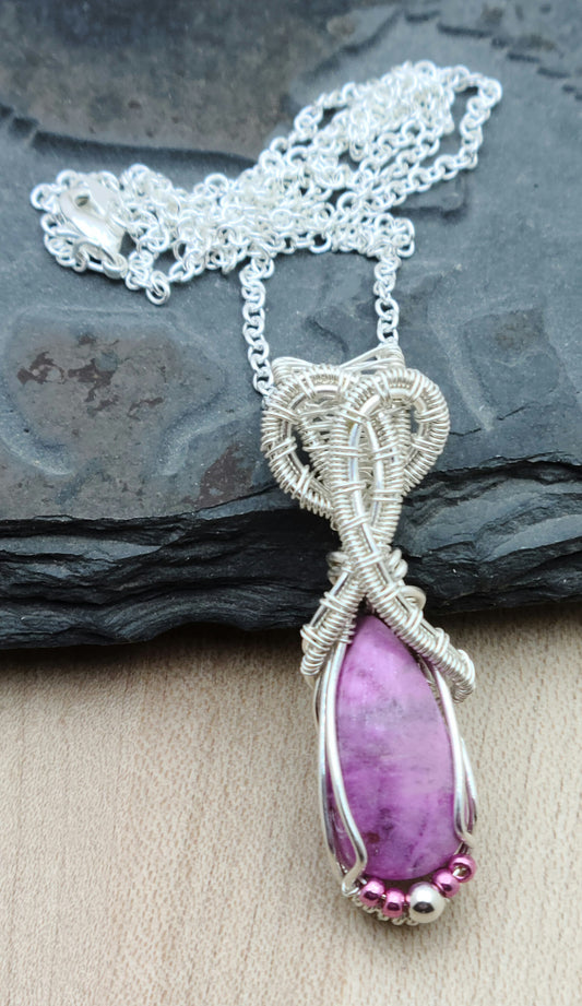 This delicate pinkish stone (with a subtle purple hue) is associated with emotional healing, love, & joy. The intricate 'frame' is woven from silver filled wire.