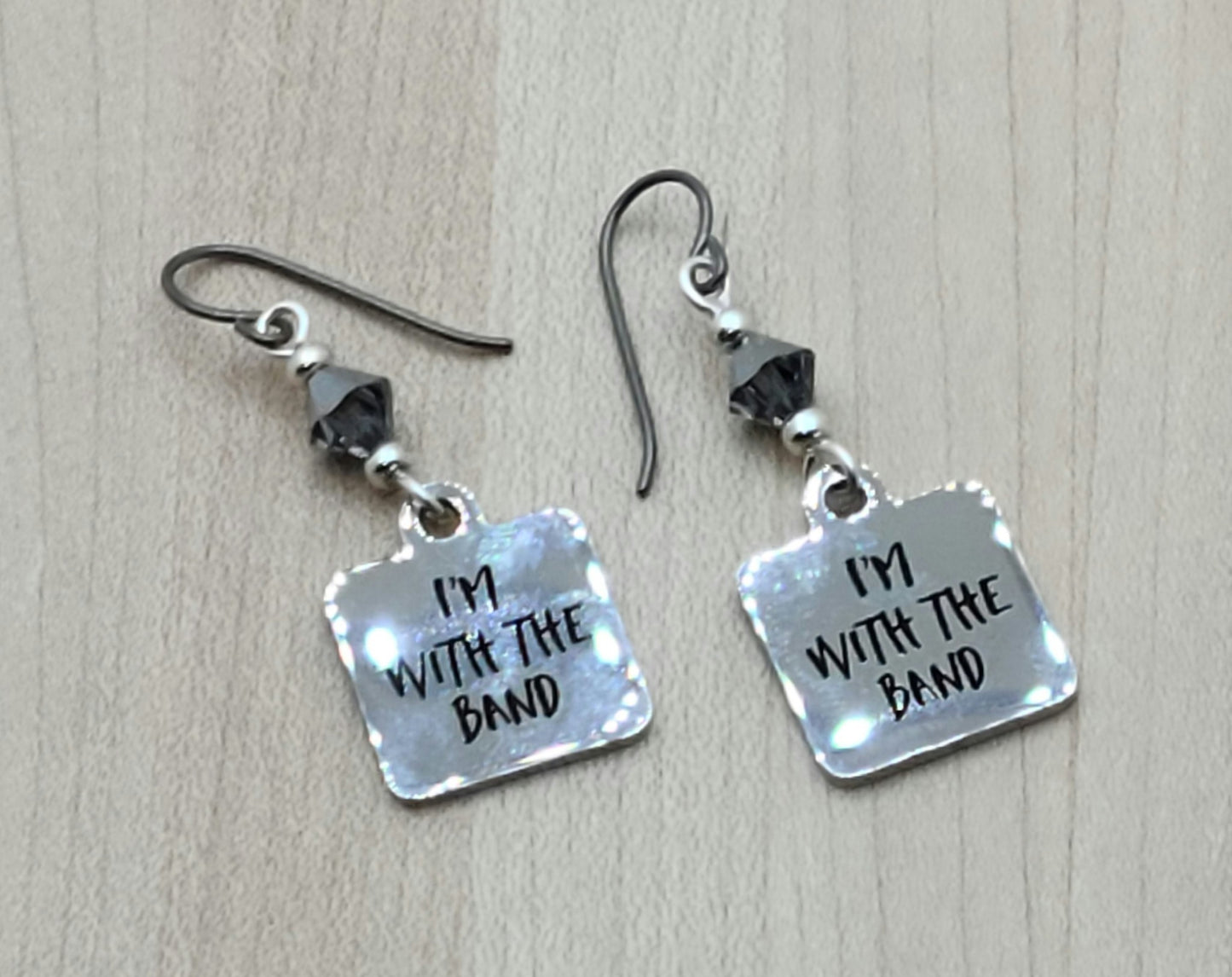 Proudly announce that you are indeed "with the band" by wearing these shiny stainless steel earrings suspended from chrome crystals.