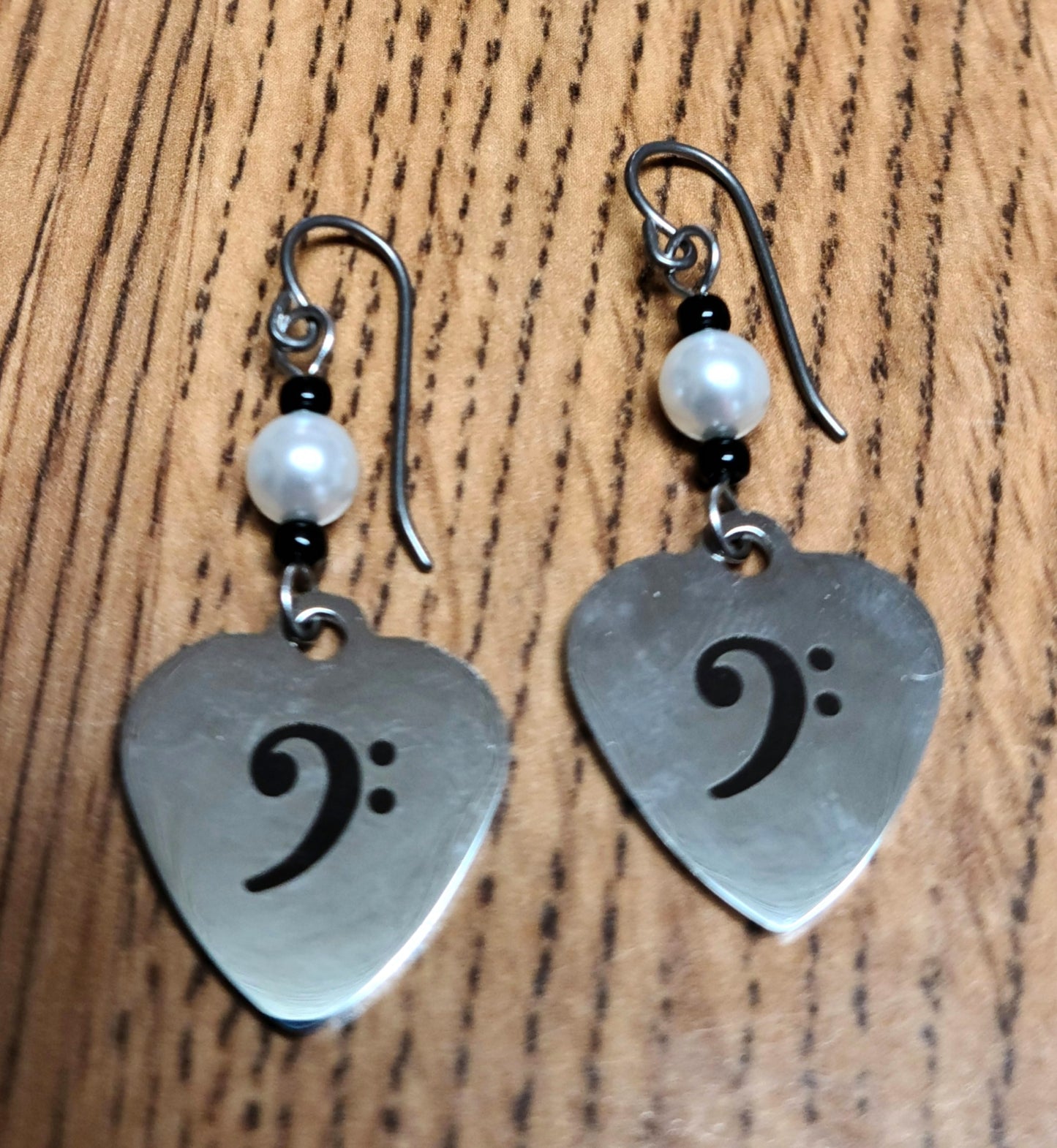 Love music? Play a bass clef instrument? Then these stainless steel hearts displaying a bass clef are for you! For added interest they hang from light silver crystal pearls.
1 3/4" with niobium (considered hypoallergenic) fish hook earwires