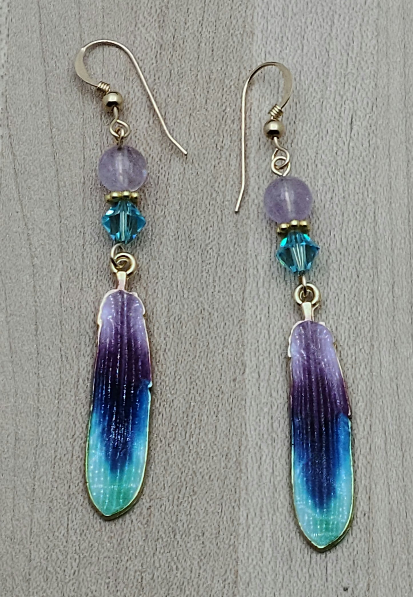 Amethyst, teal, dark blue, & gold get together for a pleasing and eye-catching attraction in these colorful gold plated feathers, accented by matching crystals! 2 7/8" with gold filled fish hook earwires