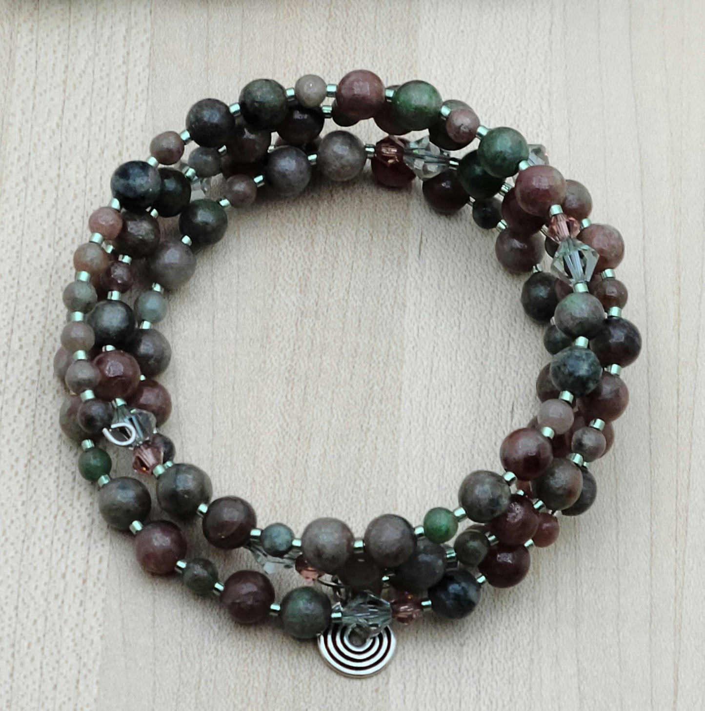 The mixed, earthy color palette of burgundy, forest green, black, & white swirls in Kashgar garnet are paired with pale green & vintage rose crystals & green Miyuki delica to create a lovely 4 row memory wire bracelet.