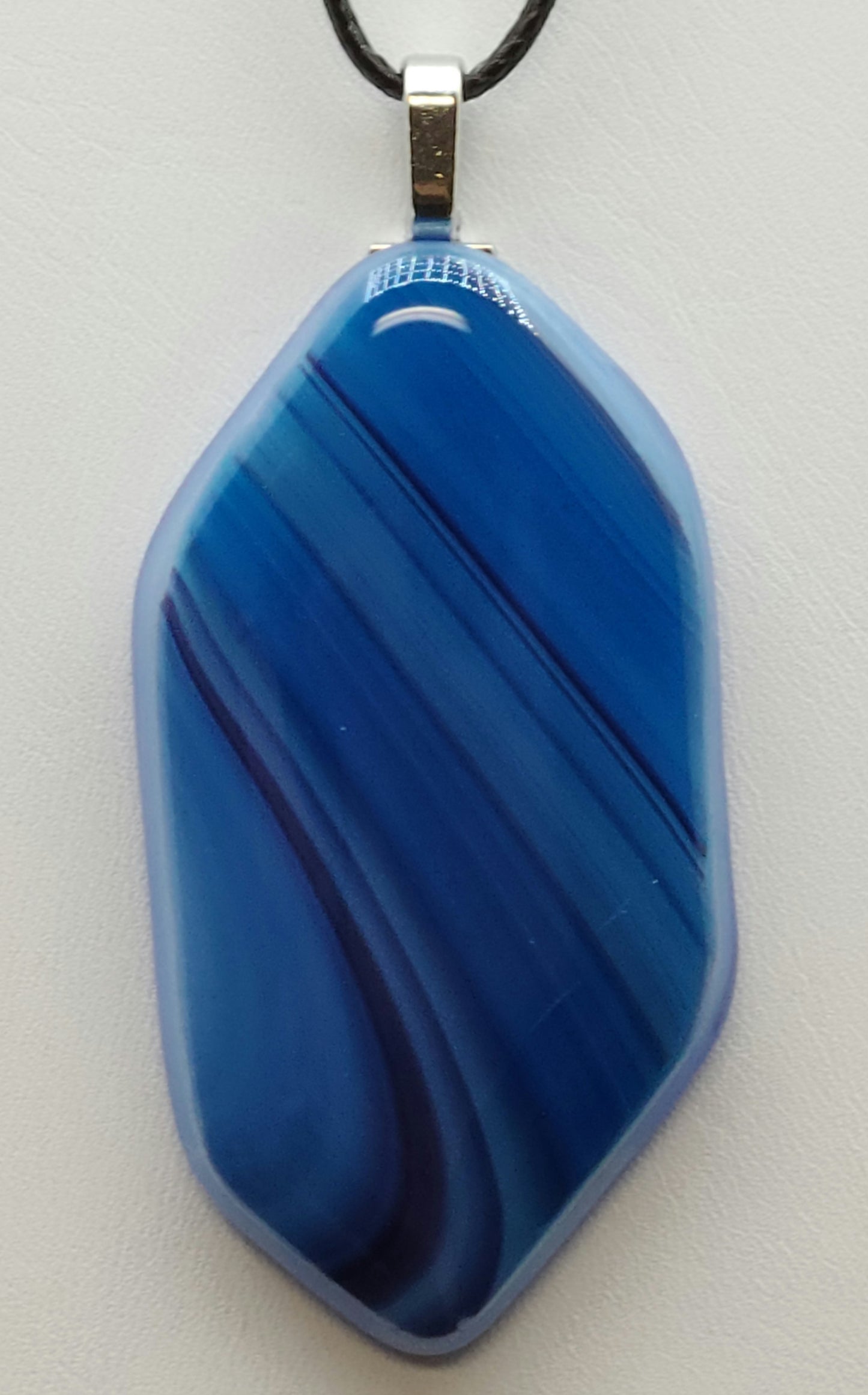 The Shades of Blue Fused Glass Pendant features a bright blue background with varying shades of blue, creating a stunning visual effect.