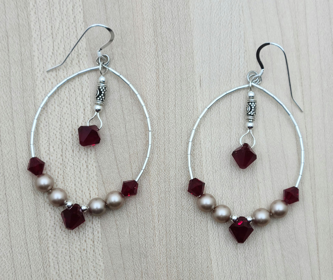 These large oval hoop earrings are eye-catching with their deep siam red crystals* and soft almond colored crystal pearls*!