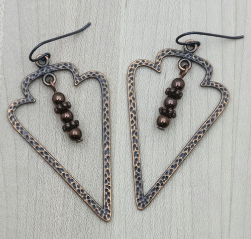 Hammered copper open arrowheads host electroplated hematite & copper daisy dangles.