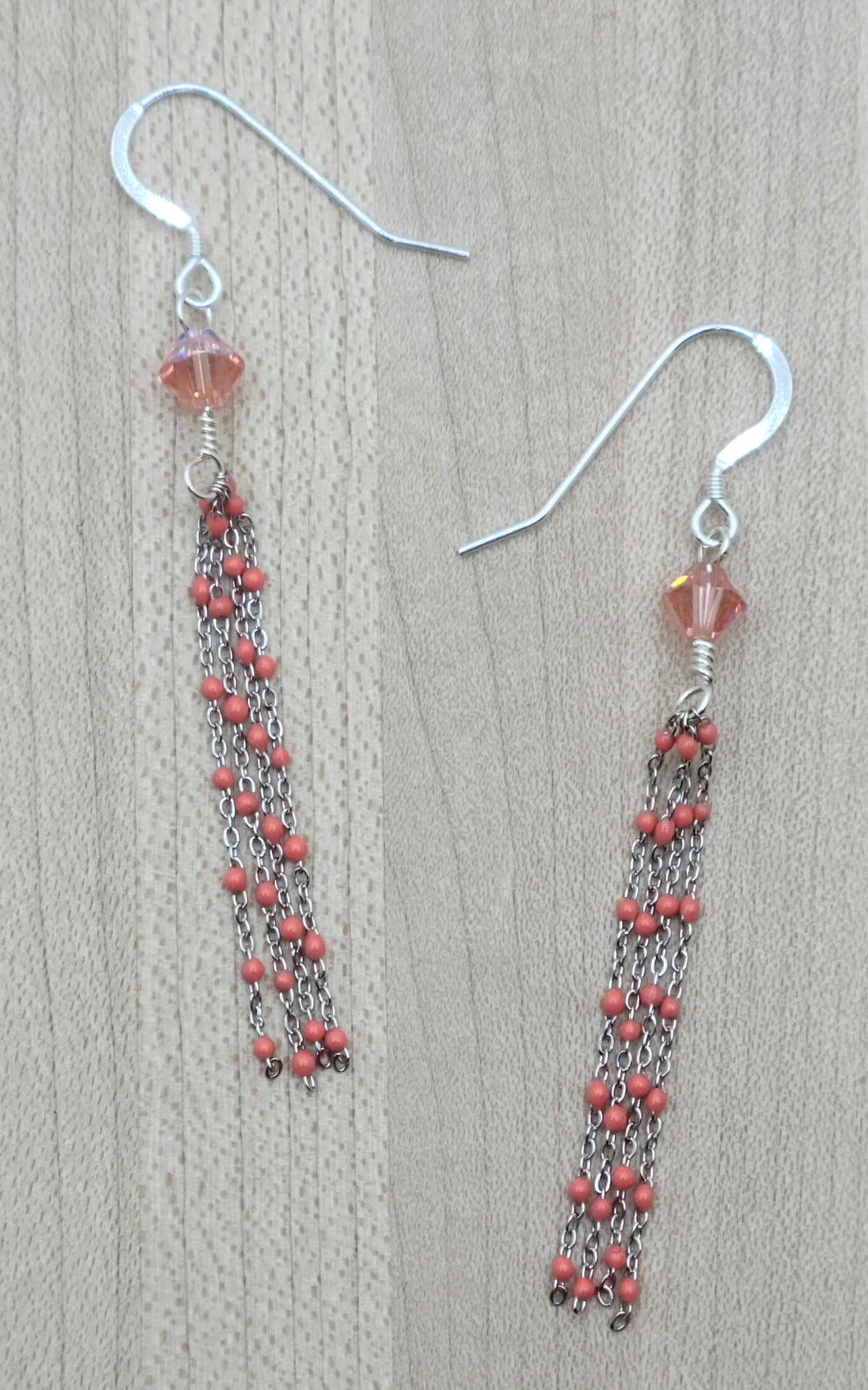 Coral dotted stainless steel tassels dangle from peach crystals in these very light-weight earrings.