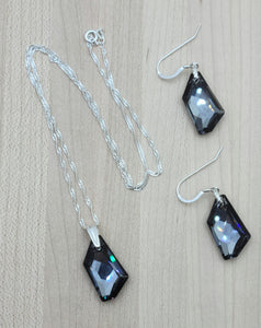 A large modern crystal pendant, dark grey with cool undertones, makes this crystal necklace both sophisticated & elegant. Matching earrings
