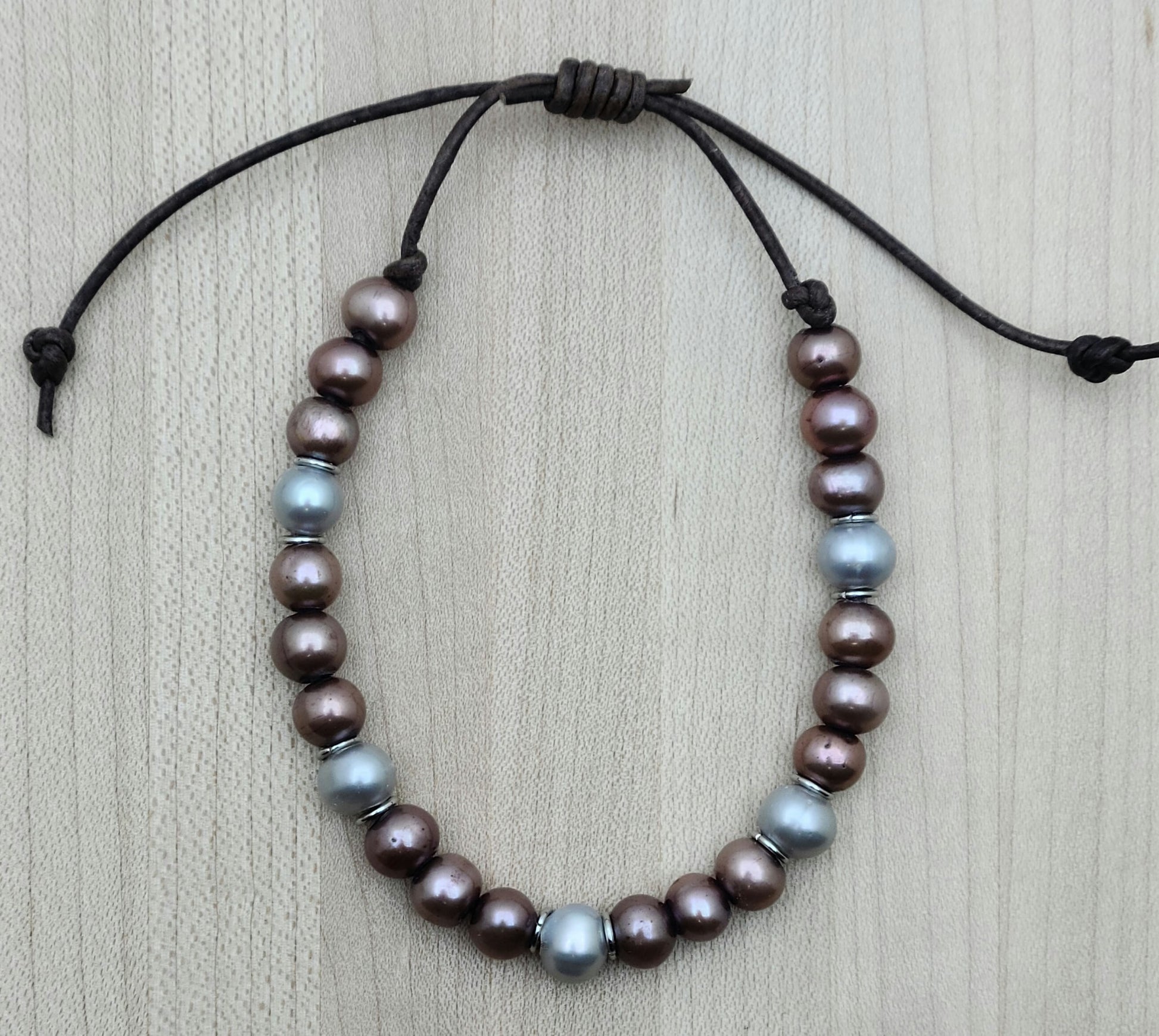 A casual leather slider bracelet of baroque freshwater in plum and silver with stainless steel rings for accent.