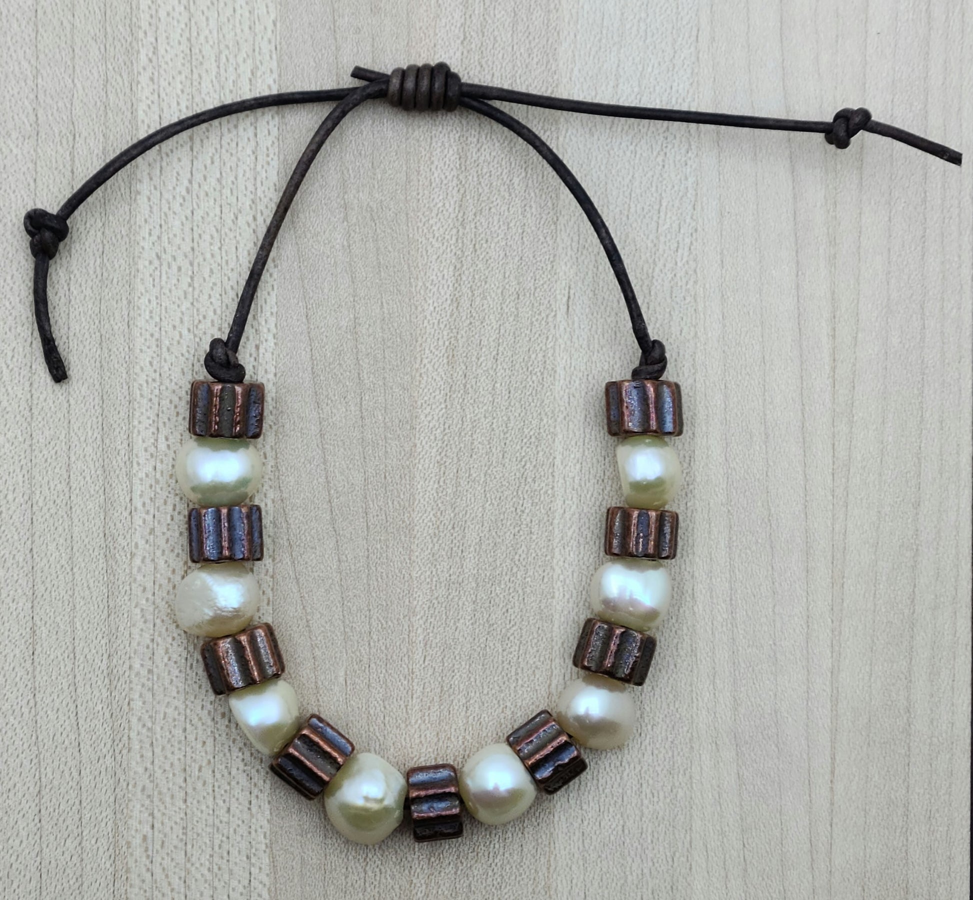 A casual leather slider bracelet of baroque freshwater in ccream and antique copper plated ceramic.