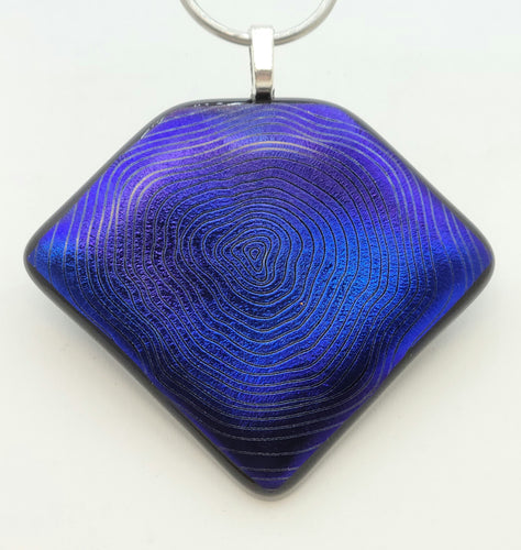 Wavy, crazy circles emanate out from the center of this bluish purple dichroic fused glass beauty!