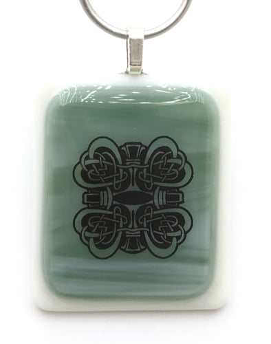 The streaked Tiffany blue glass is adorned with intricate knotted Celtic hearts in this lovely fused glass pendant.