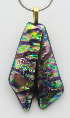 Ripple dichroic glass in rainbow colors form ribbon tails in this unique fused glass pendant!