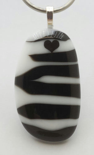 A fused glass pendant featuring zebra stripes & a tiny heart!