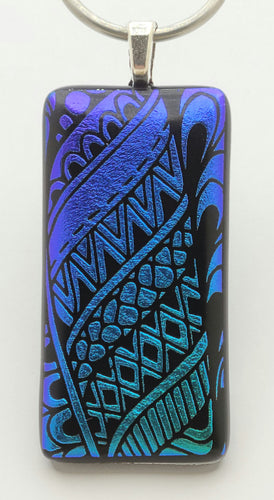 This fused glass pendant has tribal designs are etched into Indigo moving towards teal dichroic glass.