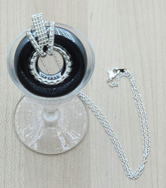 Shiny hematite donut with woven wire silver plated bail