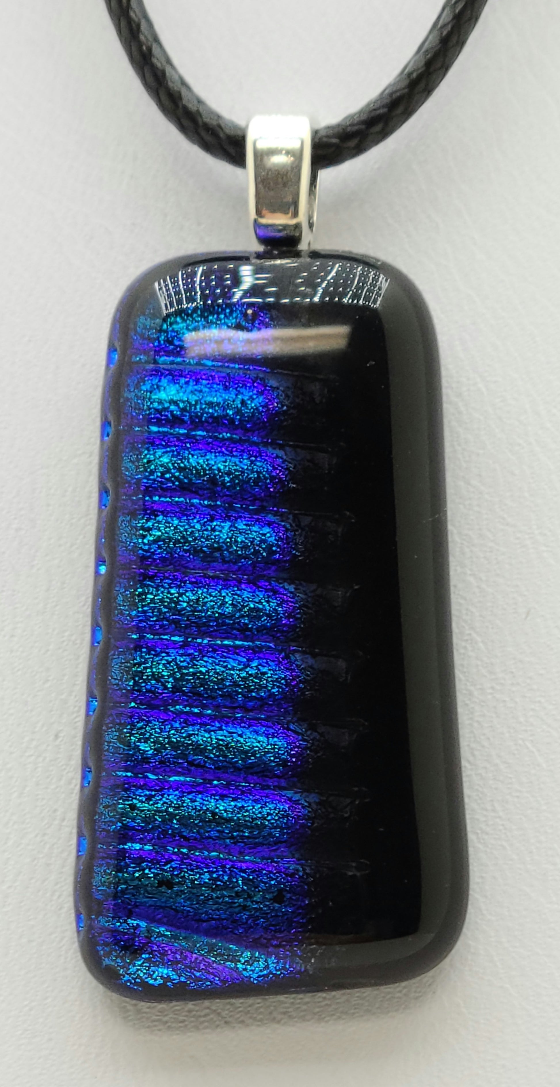 horizontal blue stripes fade to black in this small fused glass pendant.
