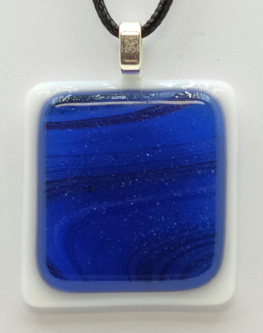 glittery swirls of blue against a white background in this fused glass pendant