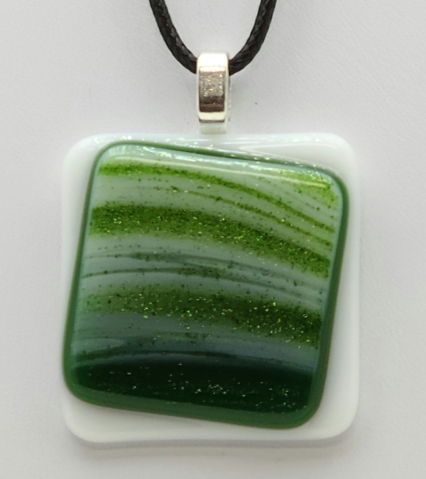 A glittery green square sits cattywampus on a white square in this fused glass pendant.