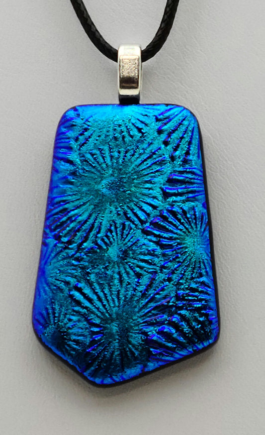 Starburst designs sing in the brilliant, deep teal blue dichroic fused glass pendant.