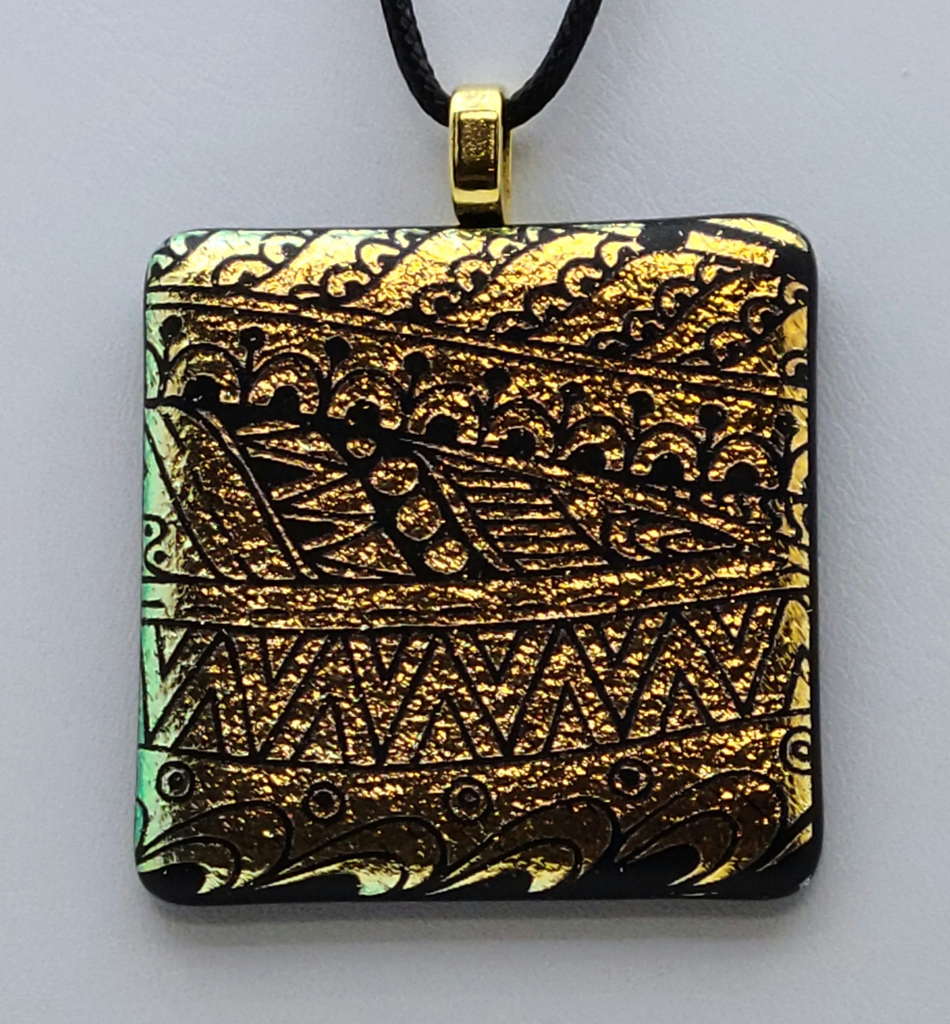 Etched tribal designs adorn gold crinkle dichroic glass in this pendant.