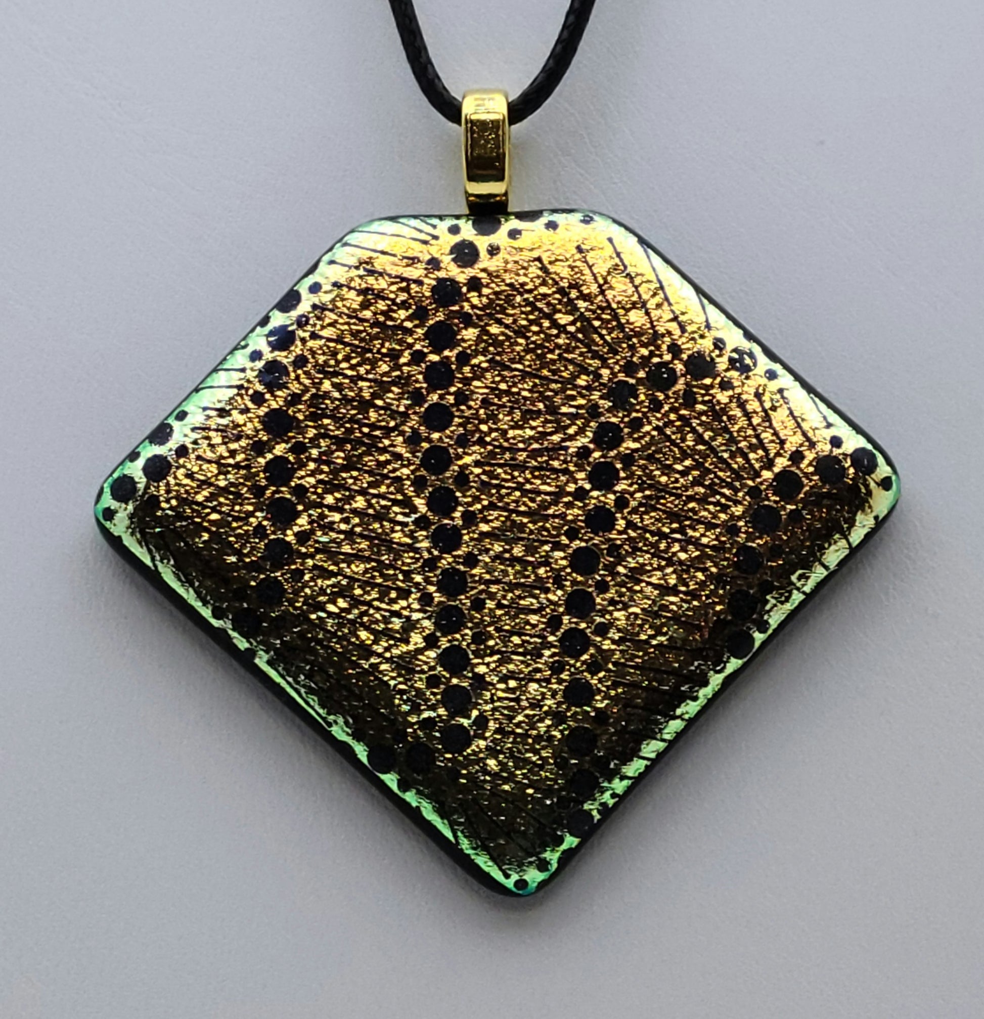 Black dots wander across gold crinkle dichroic glass in this pendant