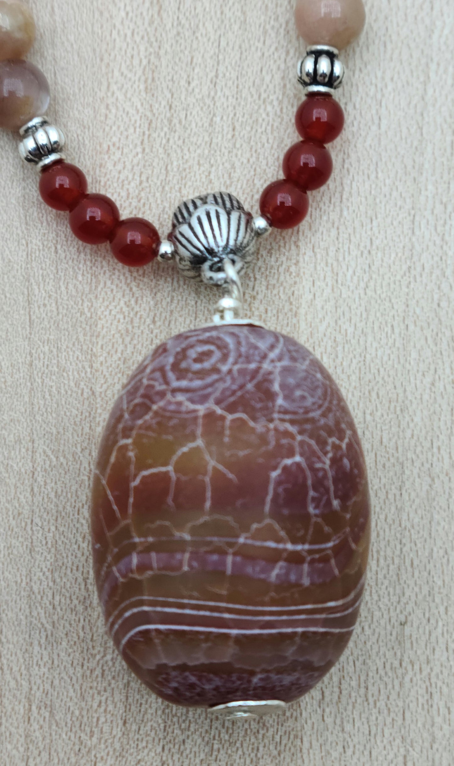 A striking Fire Agate pendant in rich red earth tones accented with subtle hints of peach and lavender.