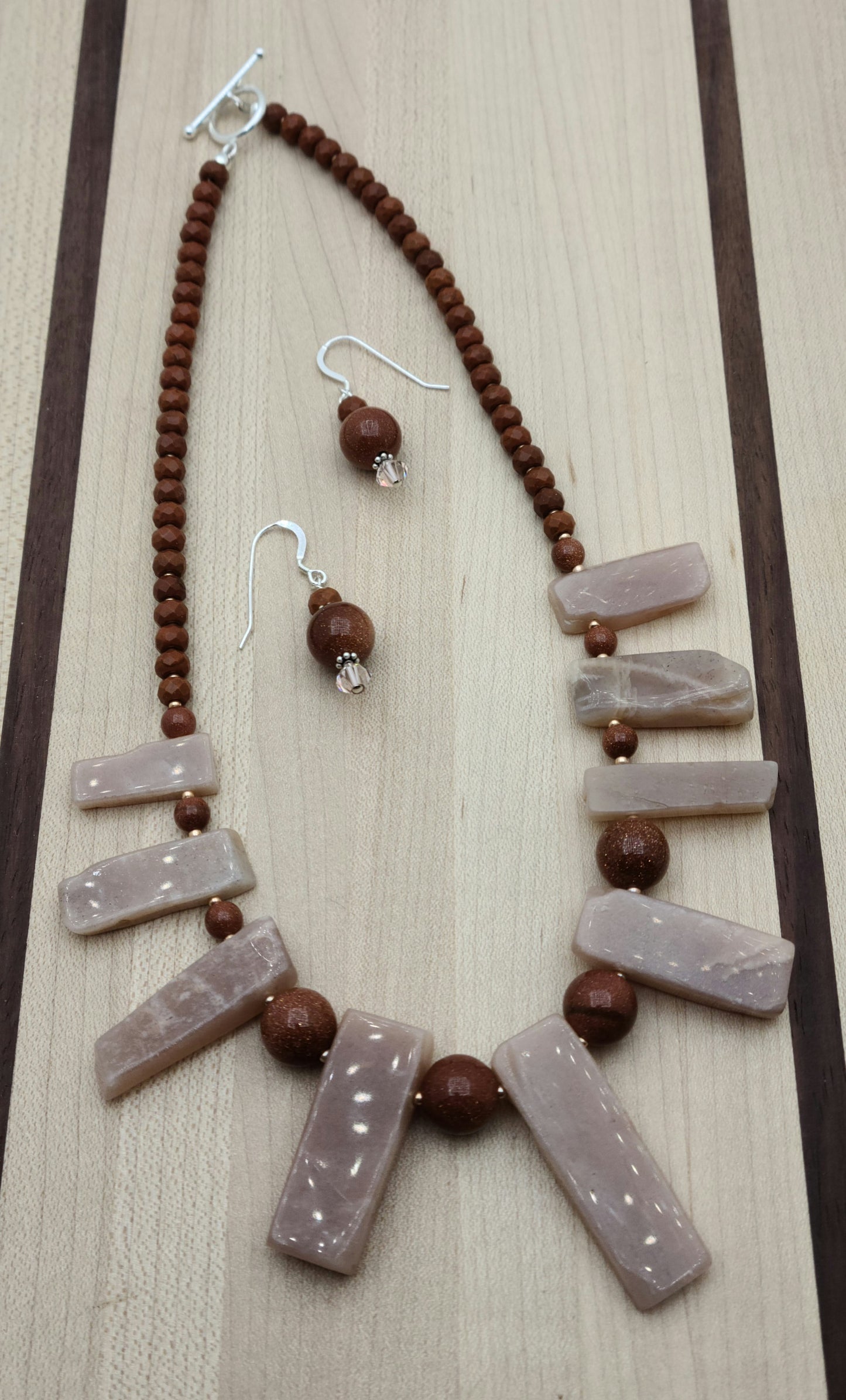 This Moonstone Slab Necklace & Earrings set features striking free-form peach moonstone slabs, enhanced by the sparkling contrast of goldstone and the warm tones of chocolate howlite rondelles.