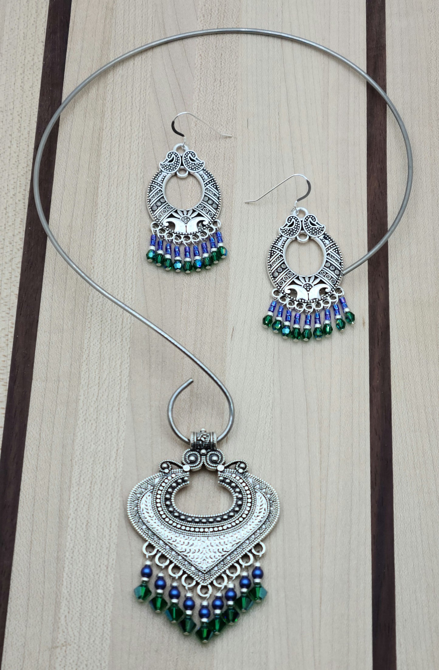 large pewter bali style pendant with bright blue and rich green dangles hanging on a stainless steel neck wire
and matching earrings