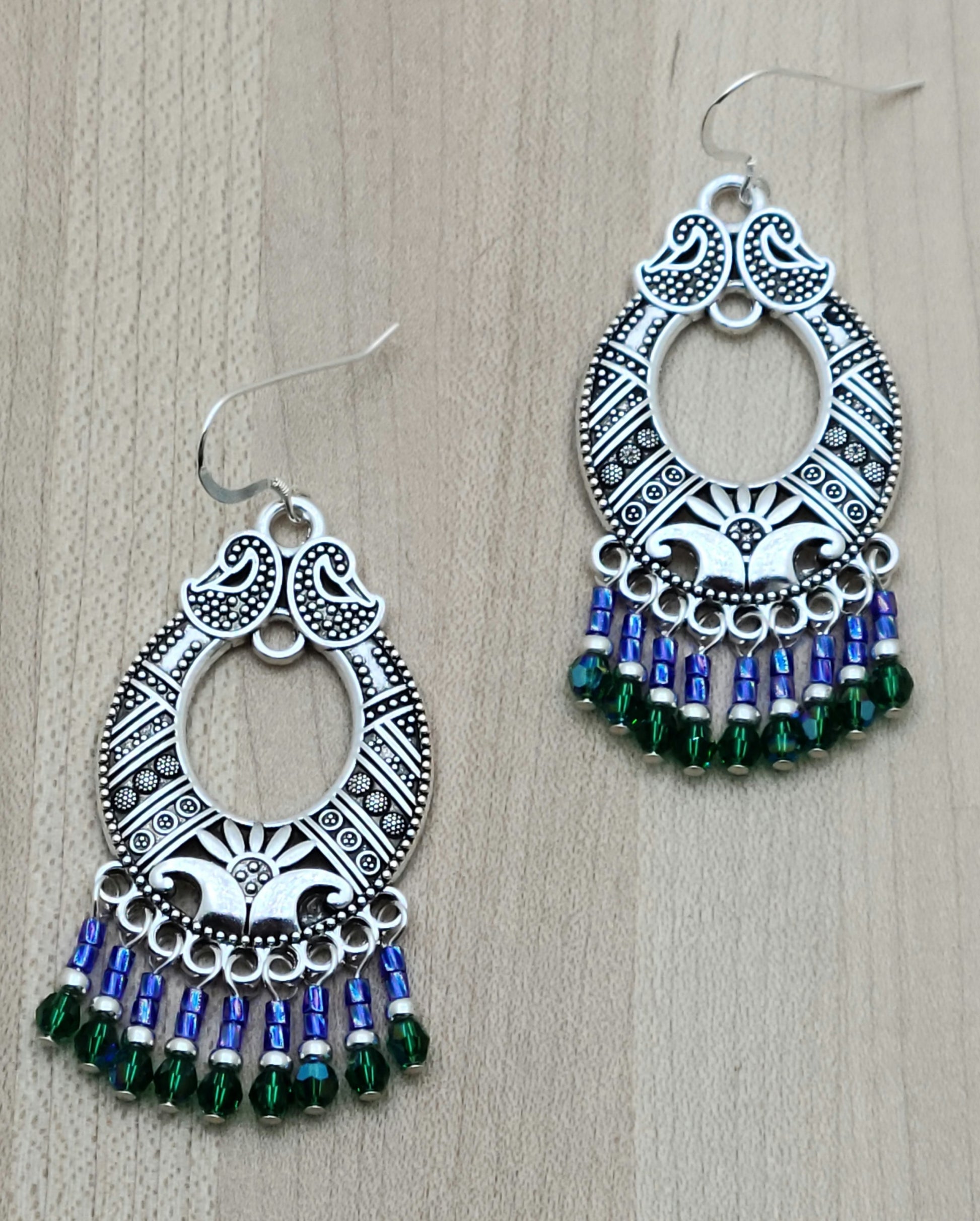large pewter bali style hoops with bright blue and rich green dangles hanging from sterling silver french hooks
