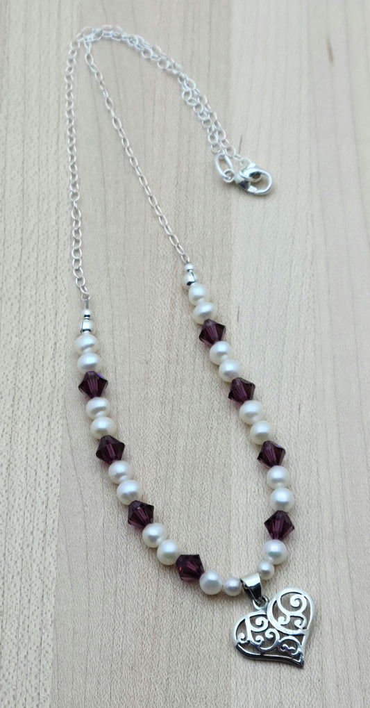 This sophisticated & sweet necklace features luminous white freshwater pearls and vibrant amethyst crystals, accented by a delicate filigree sterling silver heart pendant