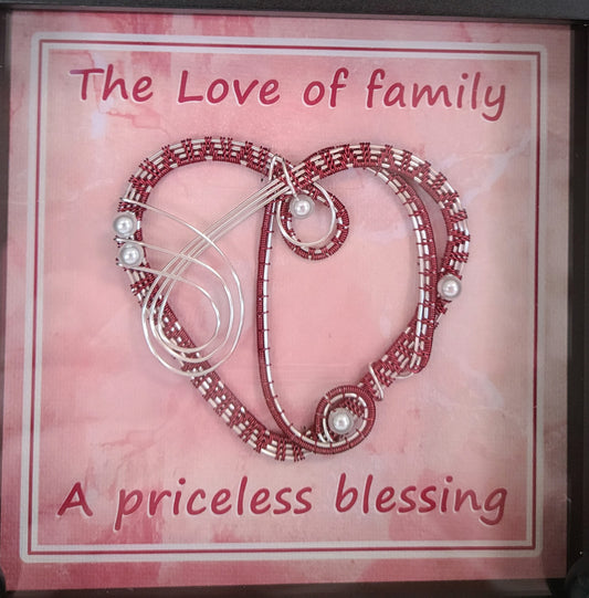 Shadow box with burgundy & silver woven wire heart. Background print of weathered fabric is printed on canvas medium and reads "The Love of family is a priceless blessing."