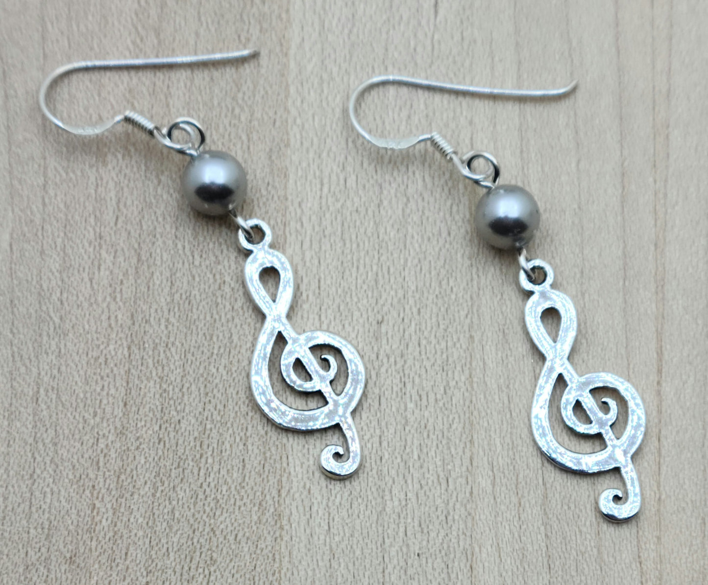 sterling silver treble clefs hang from silver crystal pearls and sterling silver fish hook ear wires